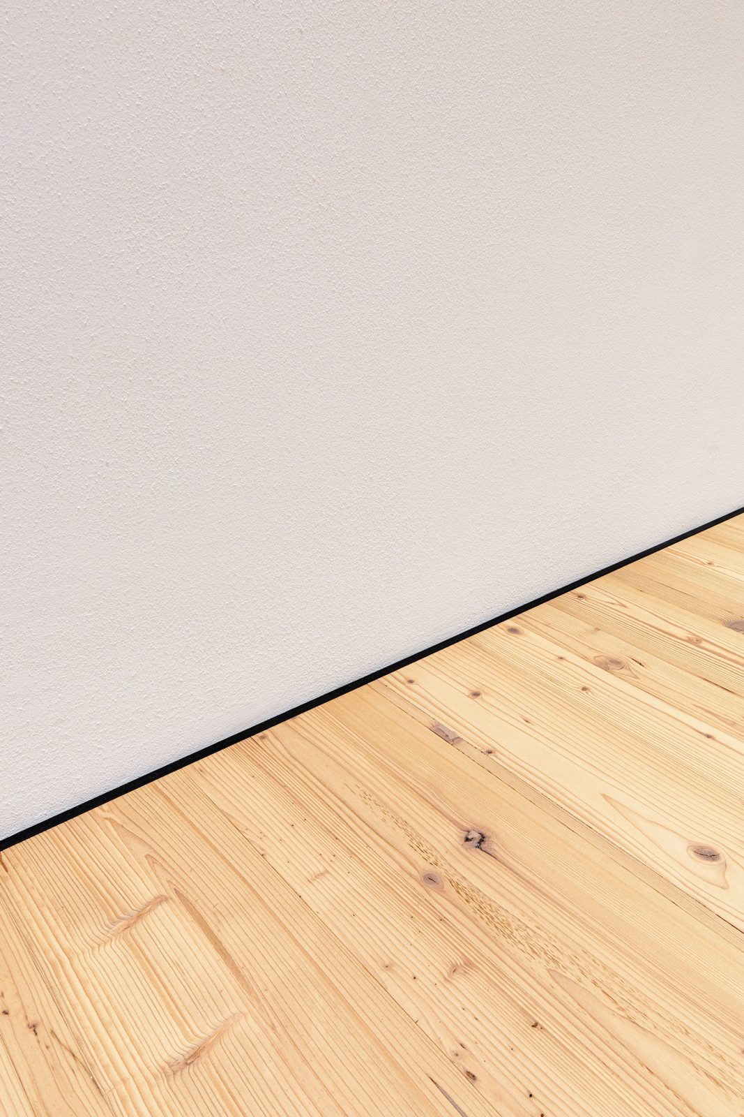 Schwarze minileiste zwischen Dielenboden und Wand