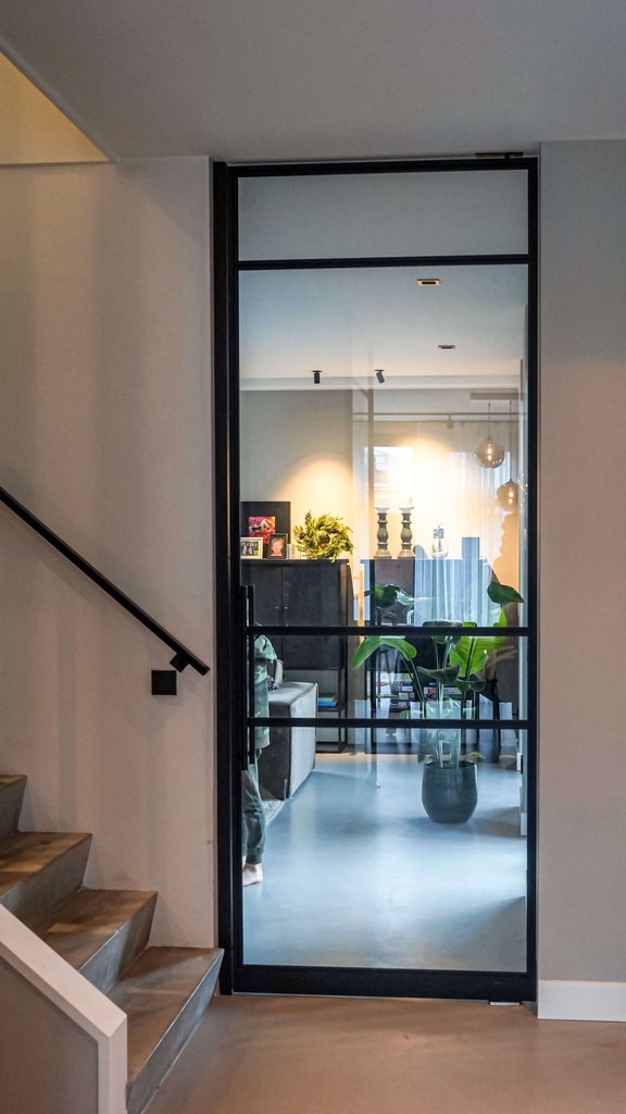 Schwarze Loft-Pivottür mit Sprossen am Treppenaufgang